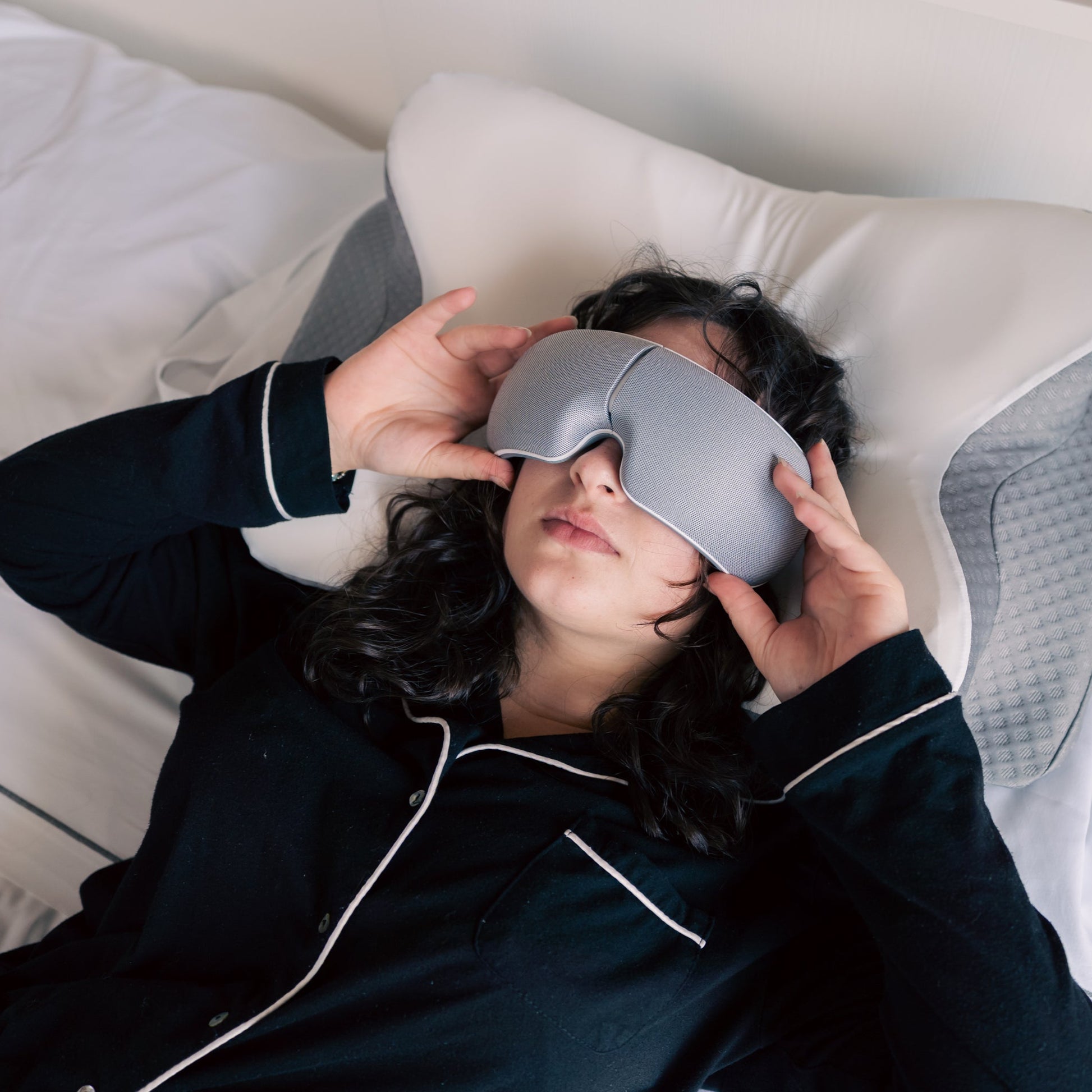 Person wearing a sleep mask in bed, indicating they are trying to sleep.