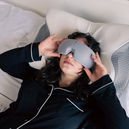 Person wearing a sleep mask in bed, indicating they are trying to sleep.